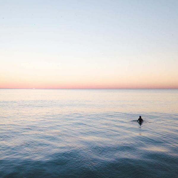 Person meditating peacefully in a minimalist space with a pink glow.